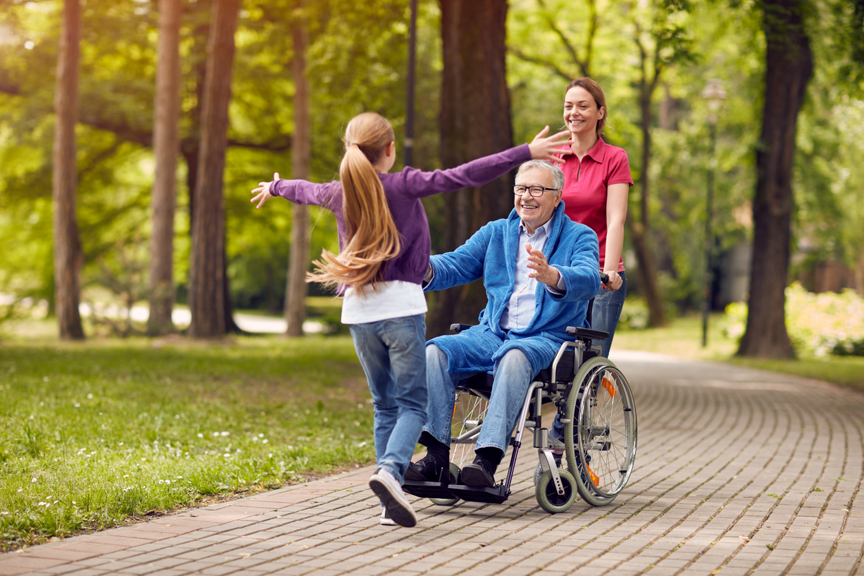 cheerful disabled grandfather in wheelchair welcoming his happy granddaughter